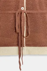 Chaqueta de punto color marrón con detalles en tono marfil en el escote en V, los puños y el ruedo. Cuenta con manga larga, cierre frontal con botones y un cinturón fino ajustable del mismo tejido.