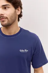 Remera blanca de algodón, de corte holgado y mangas cortas, con pequeño estampado azul en el pecho.