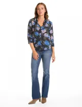 Camisa de gasa con estampado floral en tonos azules y rosados sobre fondo negro. Presenta cuello con solapa, escote en V, cierre frontal con botones y mangas tres cuartos con puños abotonados.