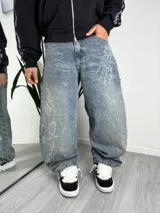 Pantalón jeans baggy de tiro medio, color celeste con efecto acid wash, corte holgado y estampado de calaveras y huesos en las piernas.