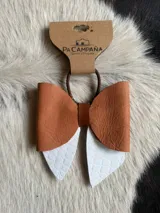 Moño para el pelo confeccionado en cuero, con diseño artesanal en tonos marrón y tostado.