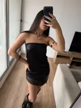 Vestido corto tipo strapless de efecto cuero negro, con detalle de puntilla en el ruedo.