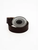 Cinto de cuero negro con hebilla ovalada de metal plateado con diseño estriado y piedra central negra.