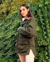 Campera tipo encerada de color azul oscuro, con cuello alto, cierre frontal de botones metálicos dorados, bolsillos frontales con solapa y bolsillos laterales en el pecho.