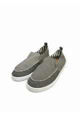 Mocasín estilo slip-on confeccionado en lona color azul oscuro, con suela blanca de goma y detalle de costuras expuestas. Interior forrado con diseño a rayas.