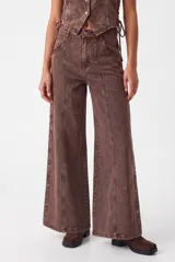 Jean de corte wide leg en color marrón chocolate con efecto acid wash. Presenta costuras frontales marcadas y detalles de botones metálicos en los laterales de las piernas.