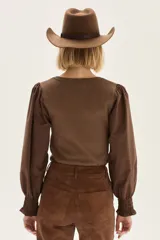 Top de calce ajustado color marrón, con escote cuadrado y mangas largas abullonadas de tela lisa. Los puños de las mangas son elastizados.