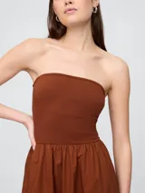 Vestido midi con diseño bicolor, presenta un cuerpo ajustado en color beige con breteles finos negros y una falda amplia de corte evasé en color negro con bolsillos laterales.