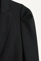 Blazer negro de corte recto de la colección Zara Studio, con solapas de muesca, cierre frontal de dos botones y bolsillos con solapa. Presenta mangas largas con pliegues estructurados en los hombros y forro interior a rayas a contraste.