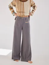 Pantalón gris de pierna ancha con tiro medio alto y pretina elastizada en la espalda. Presenta bolsillos plaque en delantera y espalda.