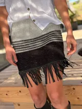 Minifalda tejida en lurex plateado y negro, con diseño a rayas horizontales y flecos con tachas en el ruedo.