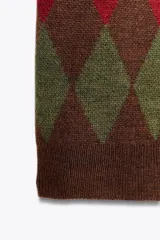 Chaqueta de punto de manga corta con cuello polo y cierre frontal de botones. Presenta un patrón de rombos (argyle) en tonos marrón oscuro, verde oliva y rojo.