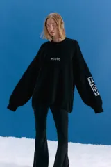 Sweater oversize de tejido de punto grueso en color negro, con cuello redondo y diseño de estampado gráfico en el pecho y en una de las mangas. Presenta un acabado desgastado que le otorga un estilo vintage.