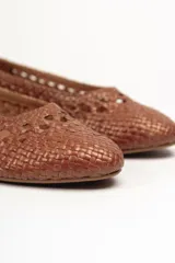 Zapato plano tipo chata, color bronce metalizado, con capellada y forro de cuero vacuno trenzado a mano. Posee un taco bajo de 2,5 cm.