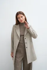 Saco corto entallado de lana fina, con cuello solapa, manga larga y cierre frontal con botones. Presenta un diseño clásico con textura de espiga en tonos tierra.