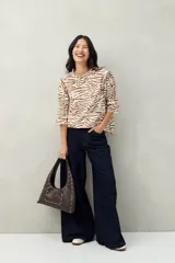 Blusa color beige con estampado abstracto en blanco, corte relajado, mangas 3/4 fruncidas y cuello con volados.