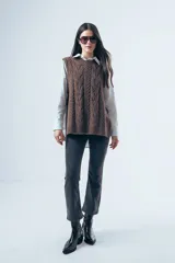 Chaleco de punto color marrón con diseño de ochos, cuello redondo y lazos laterales ajustables.