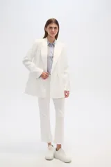 Blazer blanco de corte holgado, con cuello solapa, doble botonadura y bolsillos delanteros.
