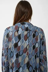 Camisa de manga larga con cuello mao y escote en V, confeccionada en algodón con un estampado geométrico abstracto en tonos azules, marrones, negros y beige.