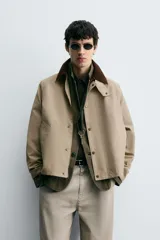 Cazadora de corte relajado confeccionada en tejido técnico con algodón. Presenta cuello de solapa en pana a contraste, cierre frontal con cremallera oculta por solapa con botones a presión, bolsillos de vivo en la cadera y manga larga.