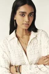 Camisa color blanco hueso con cuello clásico, tapeta con botones en la parte delantera y corte recto ligeramente oversize. Diseño con acabado de encaje.