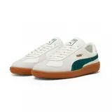 Championes Puma modelo Army Trainer, de diseño retro en color blanco con detalles en verde oscuro y suela de goma color caramelo. Presenta refuerzos de gamuza en la puntera y el logo de la marca en dorado en el lateral.