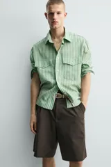 Camisa de corte relajado confeccionada en tejido fluido con mezcla de lyocell. Presenta diseño de rayas verticales, cuello solapa, manga larga con puños abotonados, bolsillos de plastrón con solapa en el pecho y cierre frontal con botones a presión.