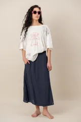 Remera blanca de manga corta y corte oversize, con bordados de motivos tropicales y marinos como palmeras, peces, estrella de mar y caracol.