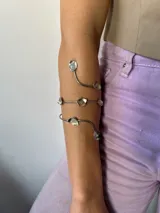 Brazalete plateado para brazo con diseño en espiral y apliques con forma de pétalos.