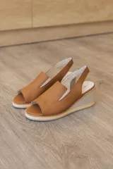 Sandalia de taco corrido confeccionada en 100% cuero vacuno, color beige. Cuenta con capellada envolvente con recorte lateral elástico y tira trasera para mayor sujeción.