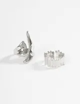 Set de dos anillos plateados de aleación de metales. Uno con diseño abstracto y forma orgánica, y el otro con un patrón de barras verticales irregulares.