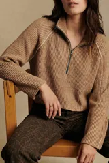 Sweater de punto acanalado color camel, con cuello alto y cierre frontal parcial. Presenta mangas largas con costuras raglán y un corte al cuerpo.