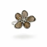 Anillo con diseño de flor, compuesto por pétalos de cristal ahumado y centro decorado con pequeñas zirconias brillantes. Base de acero plateado con estructura ajustable.