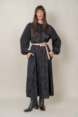 Vestido midi negro con estampado floral, mangas largas abullonadas con puños elastizados, cuello mao y cinturón fino color cobre.
