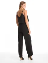 Enterito de crepe negro con diseño de capa suelta en el torso, escote en V y breteles finos ajustables. Presenta cintura definida y pantalón de pierna ancha con caída fluida, con cierre invisible en la espalda.