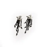 Aros colgantes con forma de estrella plateada de la que cuelgan múltiples hilos de cuentas negras y plateadas.
