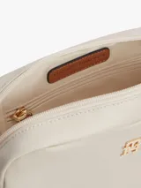 Cartera bandolera rectangular de tejido técnico color beige, con cierre de cremallera, correa tejida ajustable y extraíble, y detalle de monograma TH metálico en la parte delantera.
