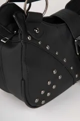 Cartera marrón de símil cuero con detalles de pespuntes y apliques de tachas metálicas. Cuenta con hebilla, dos asas fijas y un bolsillo adicional en su interior.