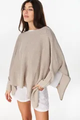 Poncho oversize de tejido de punto con hilos de lurex, color negro, con escote redondo y aberturas laterales en las mangas.
