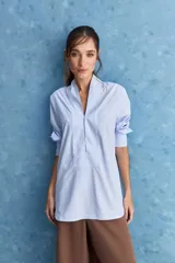 Camisa de calce relajado color celeste, con escote en V y cuello mao, mangas largas y largo extendido.