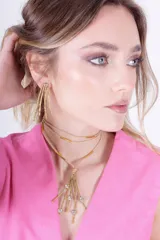 Aros colgantes dorados con forma de ramas largas.