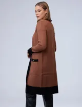 Cardigan largo tejido color marrón con ribetes negros en contraste, bolsillos delanteros y mangas largas.