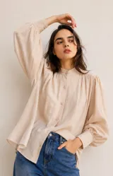 Camisa de algodón color crudo con cuello mao, cierre frontal de botones y mangas largas abullonadas con puños ajustados. Presenta frunces en los hombros y un corte relajado.