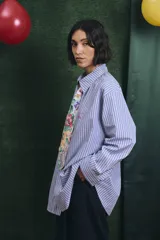 Camisa de corte oversize con estampado a rayas verticales en tonos azul y blanco, cuello clásico y cierre frontal con botones.