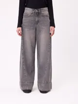 Jean de corte wide leg en color gris con efecto lavado, presenta costuras laterales decorativas y un ruedo ancho con terminación deshilachada.