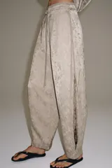 Pantalón de tiro medio de ZARA WOMAN COLLECTION, confeccionado en hilatura de viscosa con tejido jacquard de estampado floral sutil en tono beige. Presenta pierna ancha, acabado en pliegue y cintura ajustable con cordón de lazada.