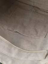 Bolso tipo tote de paja trenzada con diseño a rayas en tonos beige y verde oscuro, asas largas de cuero tostado y costuras visibles en los laterales.