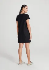 Vestido corto marrón de corte recto y holgado, con mangas cortas con vuelta, cuello redondo y un bolsillo aplicado en el pecho.