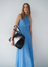 Vestido midi celeste a rayas verticales, sin mangas, con cuello camisero, cierre frontal con botones y cinturón forrado con hebilla.