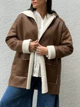 Tapado de eco cuero gamuzado color marrón con interior y bordes de corderito sintético color crema. Presenta diseño con capucha, bolsillos frontales y corte relajado.
